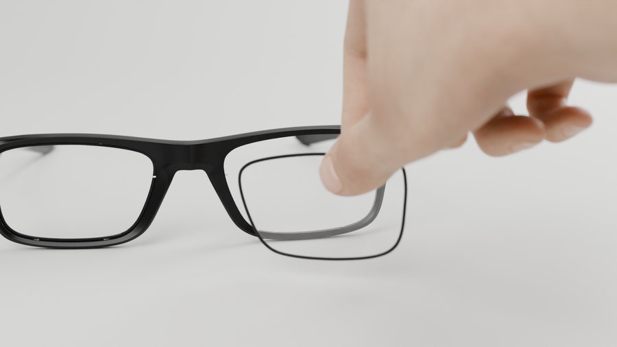 A hand removes a lens from the frame
